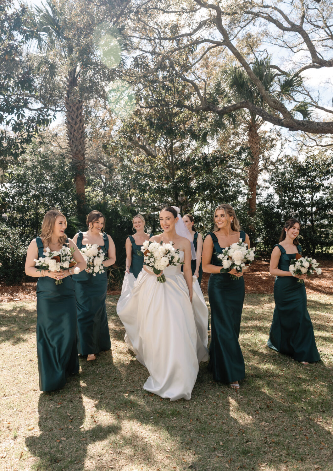Bride and bridesmaids walk in a line outside taking photos