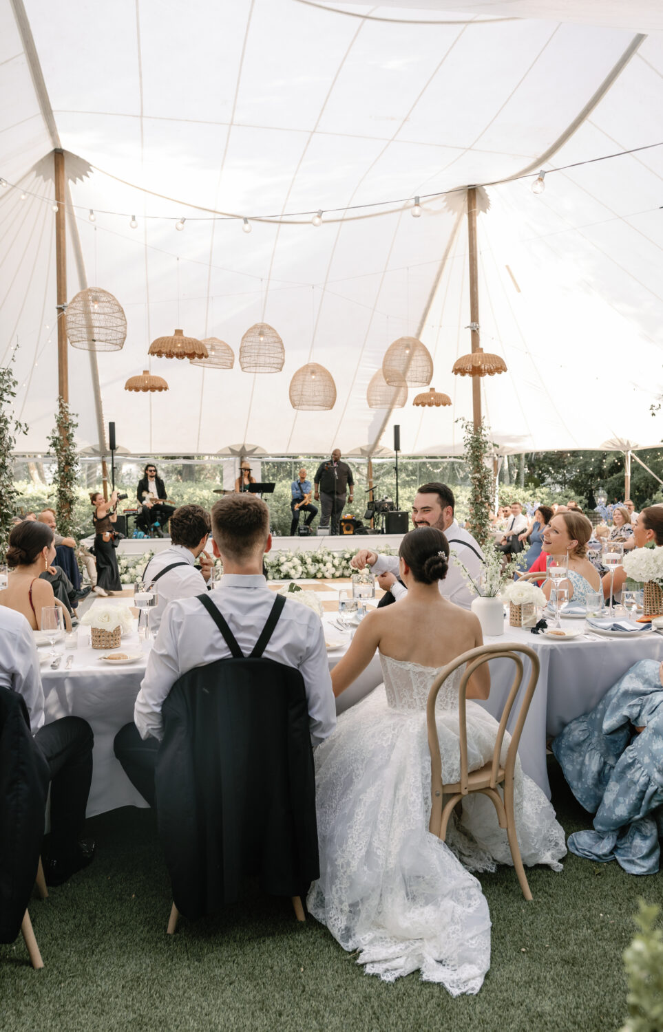 bride and groom hold hands while the father delivers a heartwarming speech 
