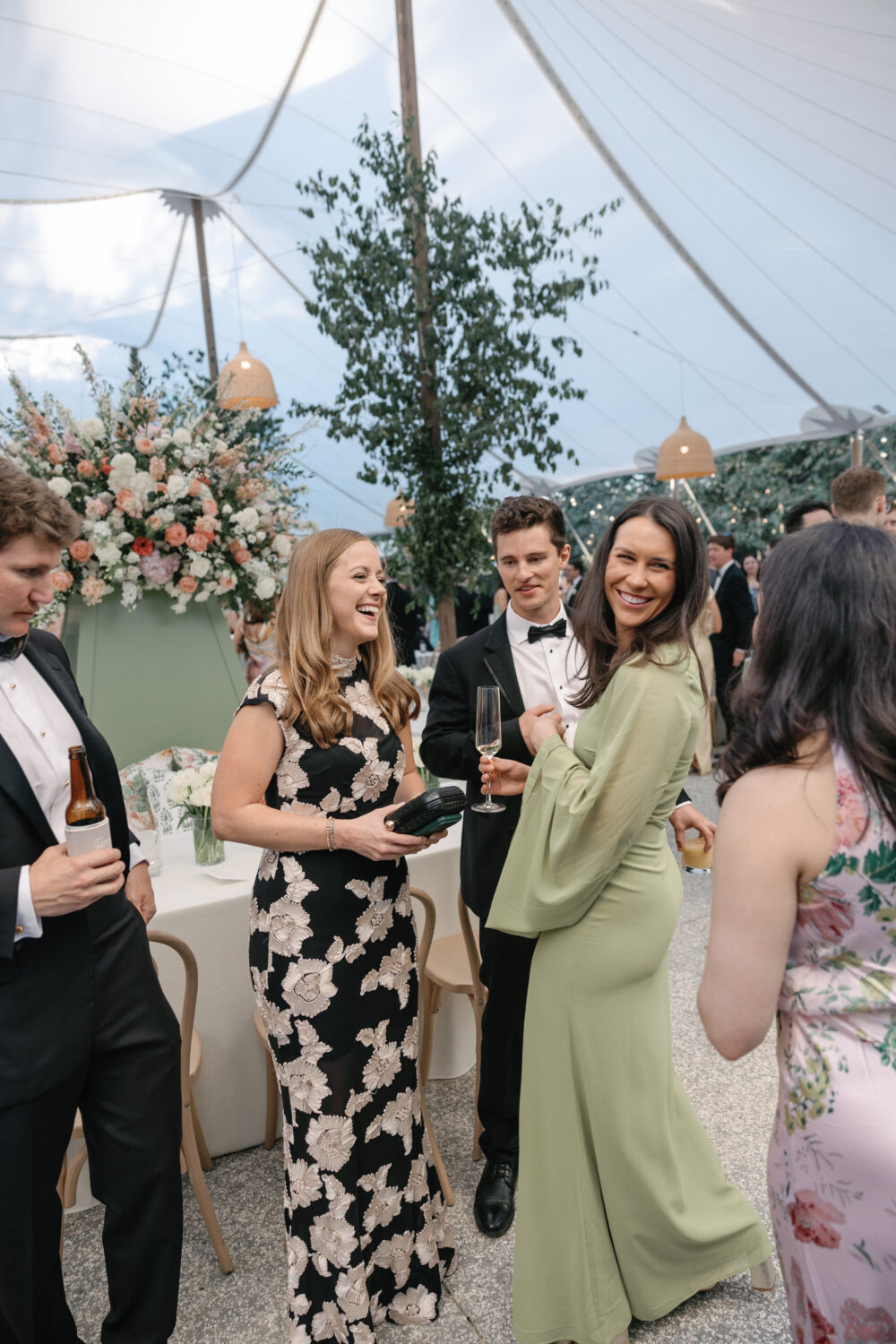 Guests laugh at cocktail hour under a tented reception